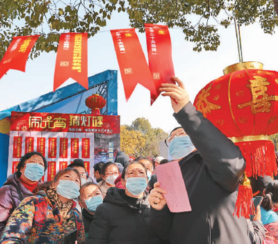 江蘇省南通市組織20個城市社區(qū)開展“一刻鐘便民生活圈”試點(diǎn)。2023南通鄰里生活節(jié)活動上，近50家品牌連鎖企業(yè)、醫(yī)療服務(wù)機(jī)構(gòu)、電商平臺、行業(yè)協(xié)會等商貿(mào)企業(yè)，將優(yōu)惠商品、優(yōu)質(zhì)服務(wù)送到居民家門口，提供消費(fèi)便利，展現(xiàn)城市溫度。活動中，購花燈、猜燈謎、專家義診、家政服務(wù)、優(yōu)惠商品等內(nèi)容豐富多彩。圖為居民在猜燈謎。  許叢軍攝（人民圖片）